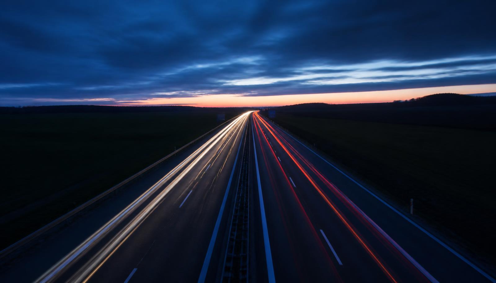 Autobahn in der Dämmerung mit Lichtspuren fahrender Fahrzeuge